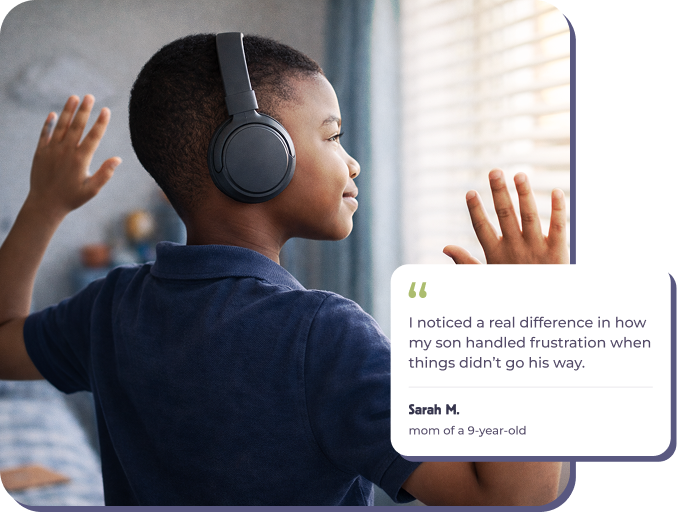 A young boy wearing headphones looks out a window with his hands near the glass.