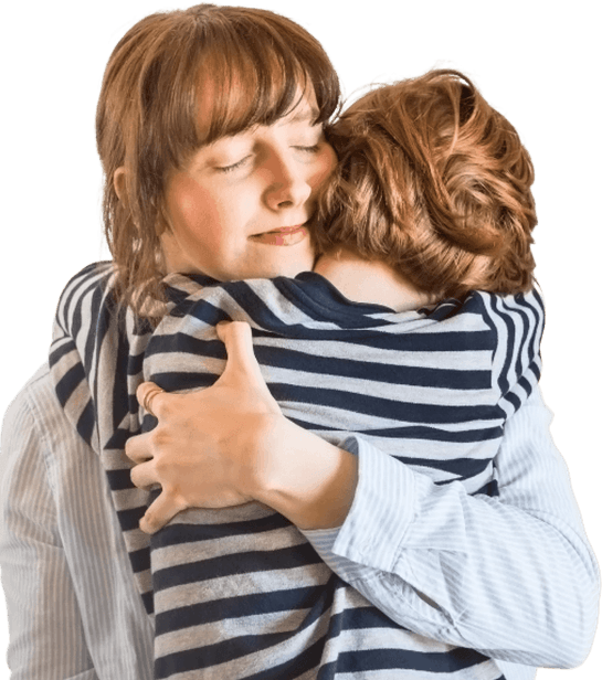 A woman with her eyes closed hugs a young child, whose back is to the camera.