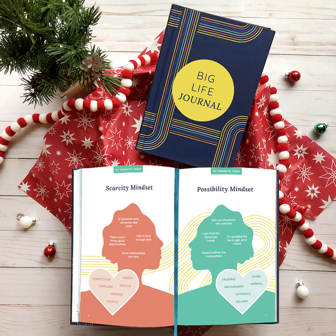 A 'Big Life Journal' open to pages on mindset, resting on Christmas-themed wrapping paper and decorations.