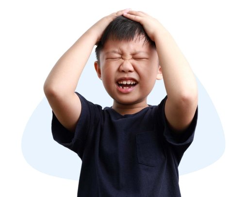 A young Asian boy in a dark t-shirt holds his head with a distressed expression.