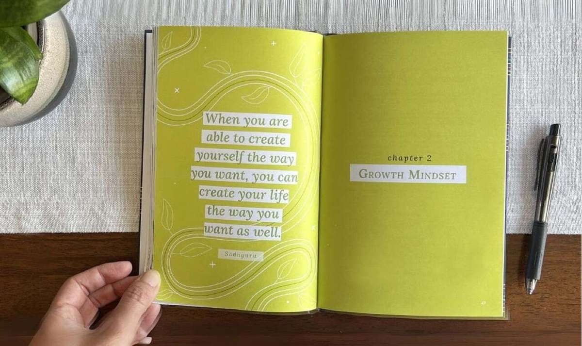 A person holds open a book with lime green pages, showing a quote and a chapter title.