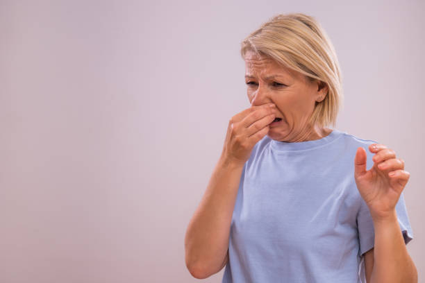 Woman pinching her nose, appearing to react to a bad smell.