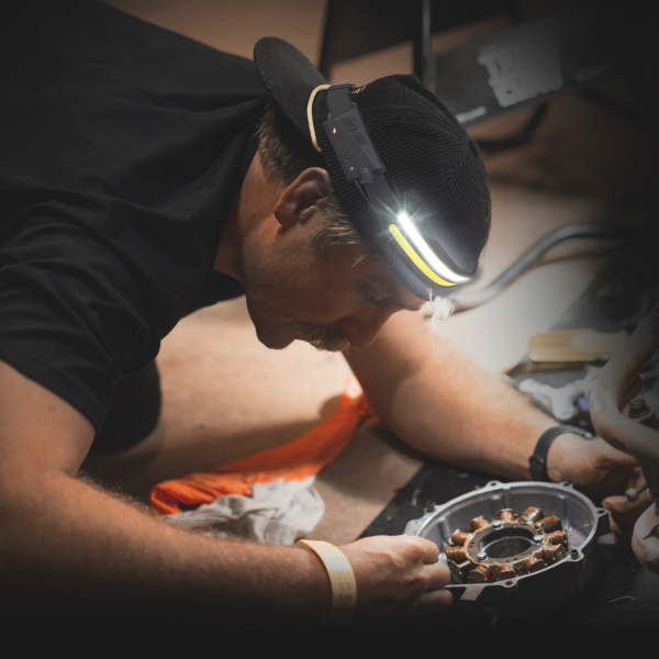 Person wearing headlamp working on a mechanical device.