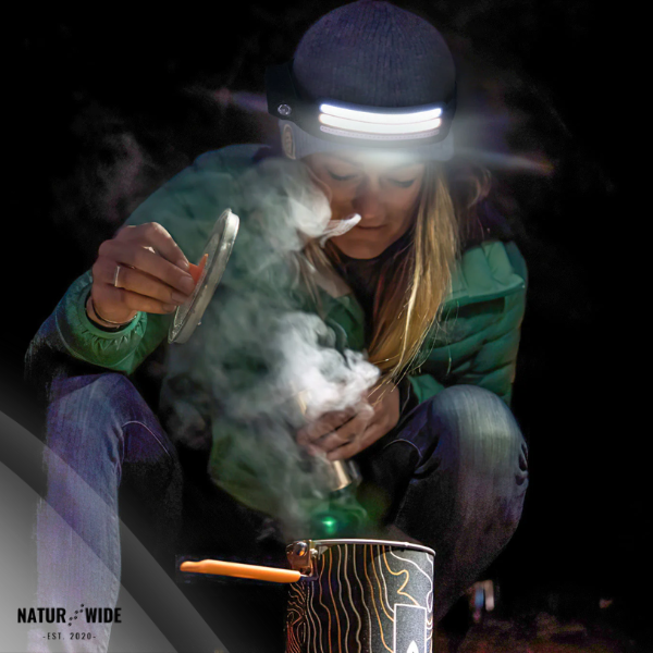 Person wearing headlamp cooking with steam rising from a pot.