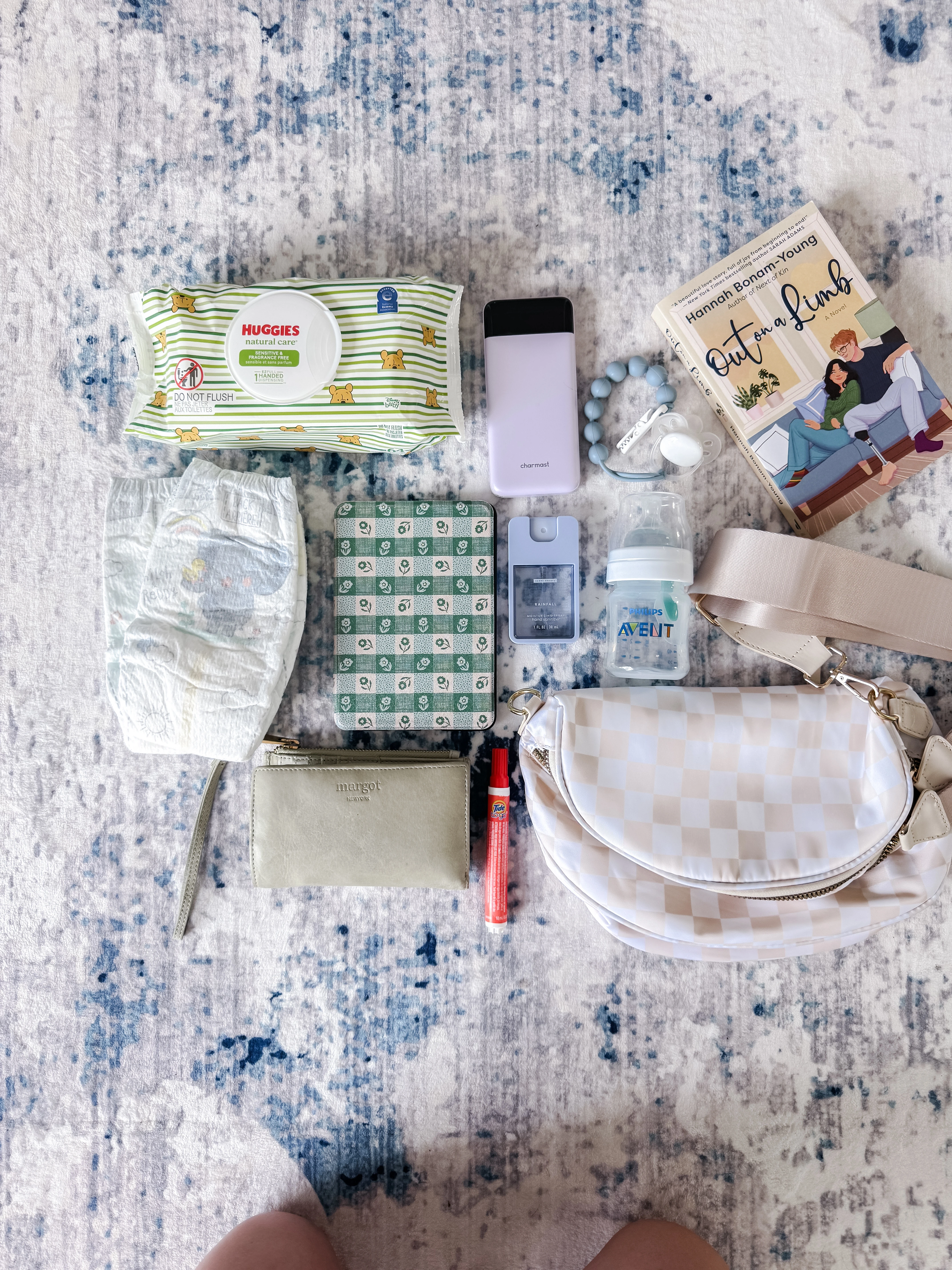 Assorted baby items and a book arranged on a patterned rug.