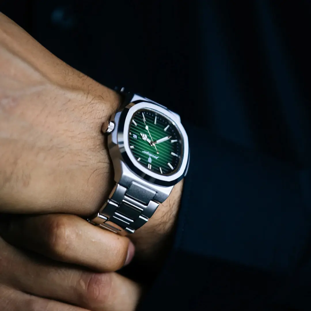 Person wearing a silver watch with a green dial.