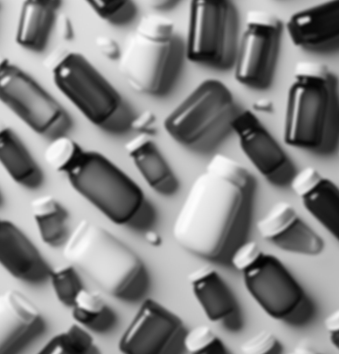Blurred image of various medicine bottles and pills on a surface.