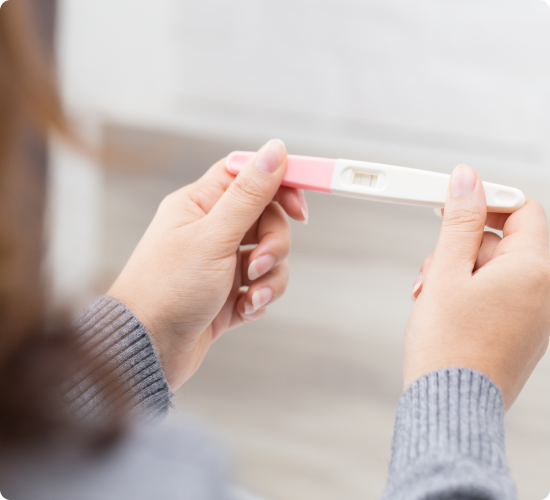 A person holds a pregnancy test showing a positive result with two lines.