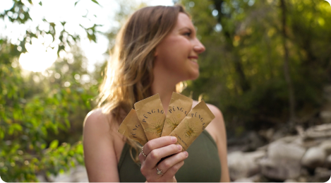 Person holding packets outdoors in a forest setting.