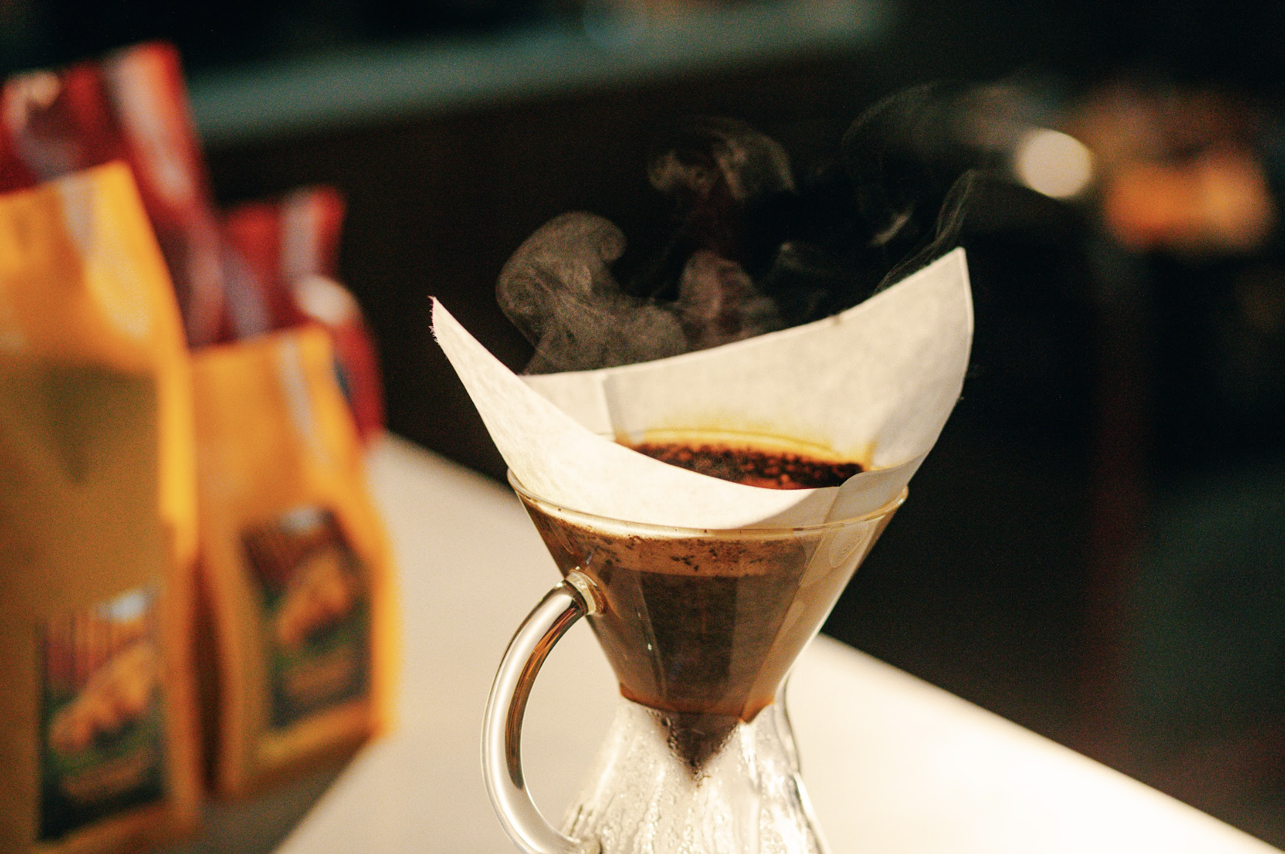Pour-over coffee brewing with steam rising from a glass carafe.