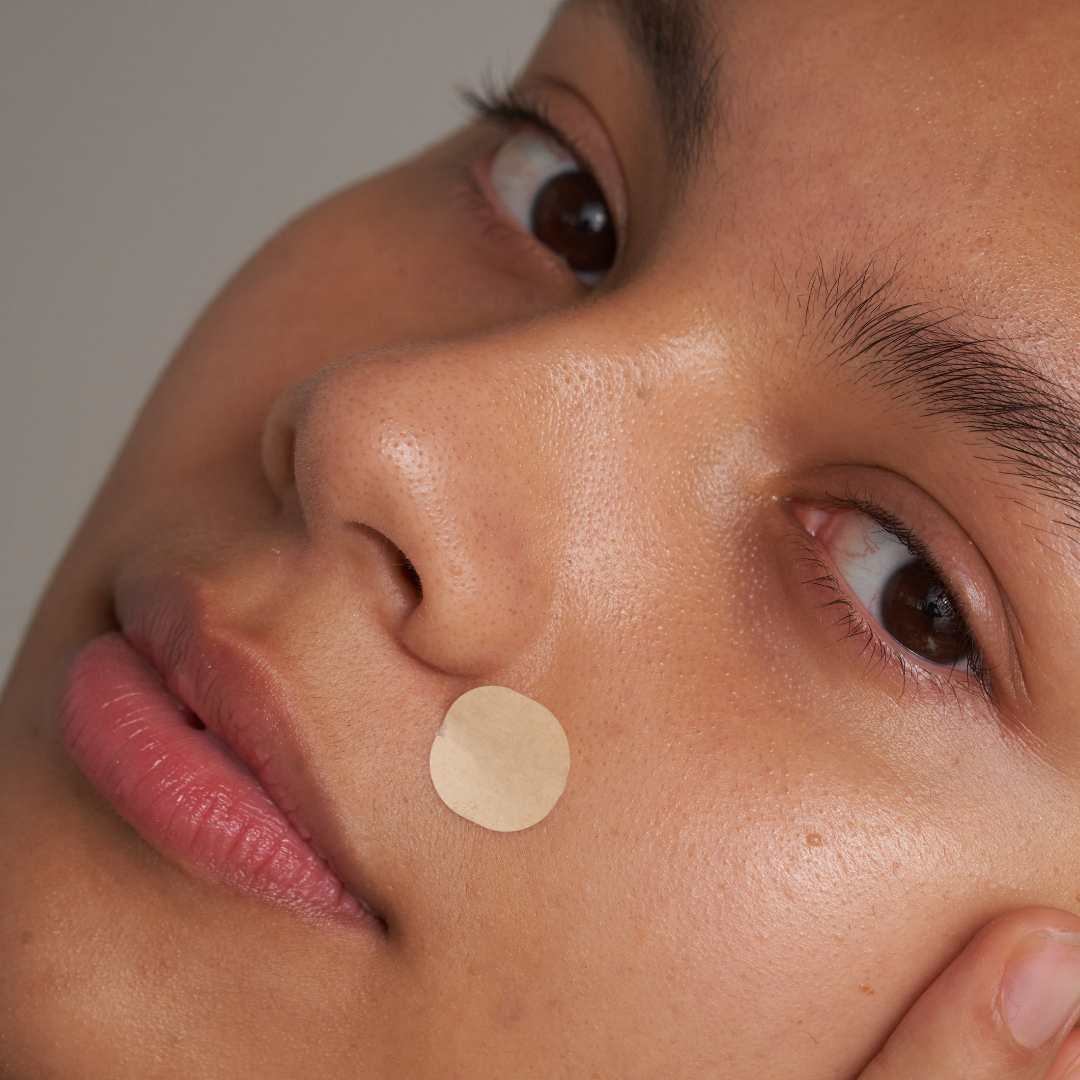 Close-up of a person's face with a small adhesive patch on the cheek.