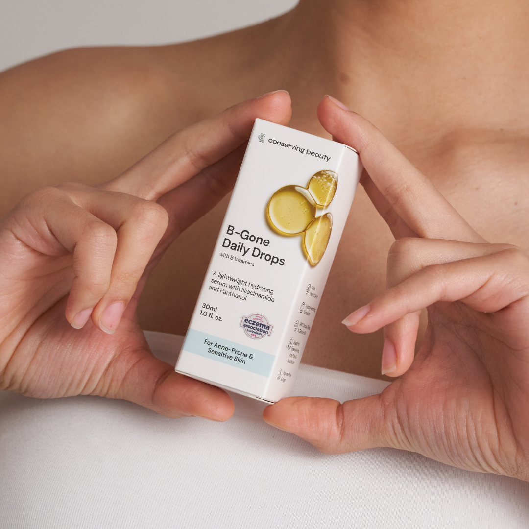 Hands holding a box of 'B-Gone Daily Drops' skincare product.