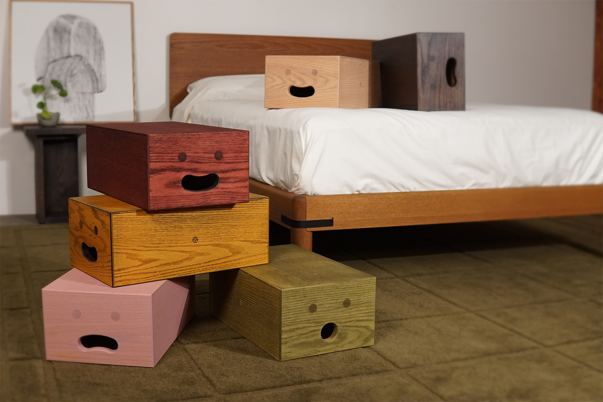 Colorful wooden boxes with facial expressions beside a bed.