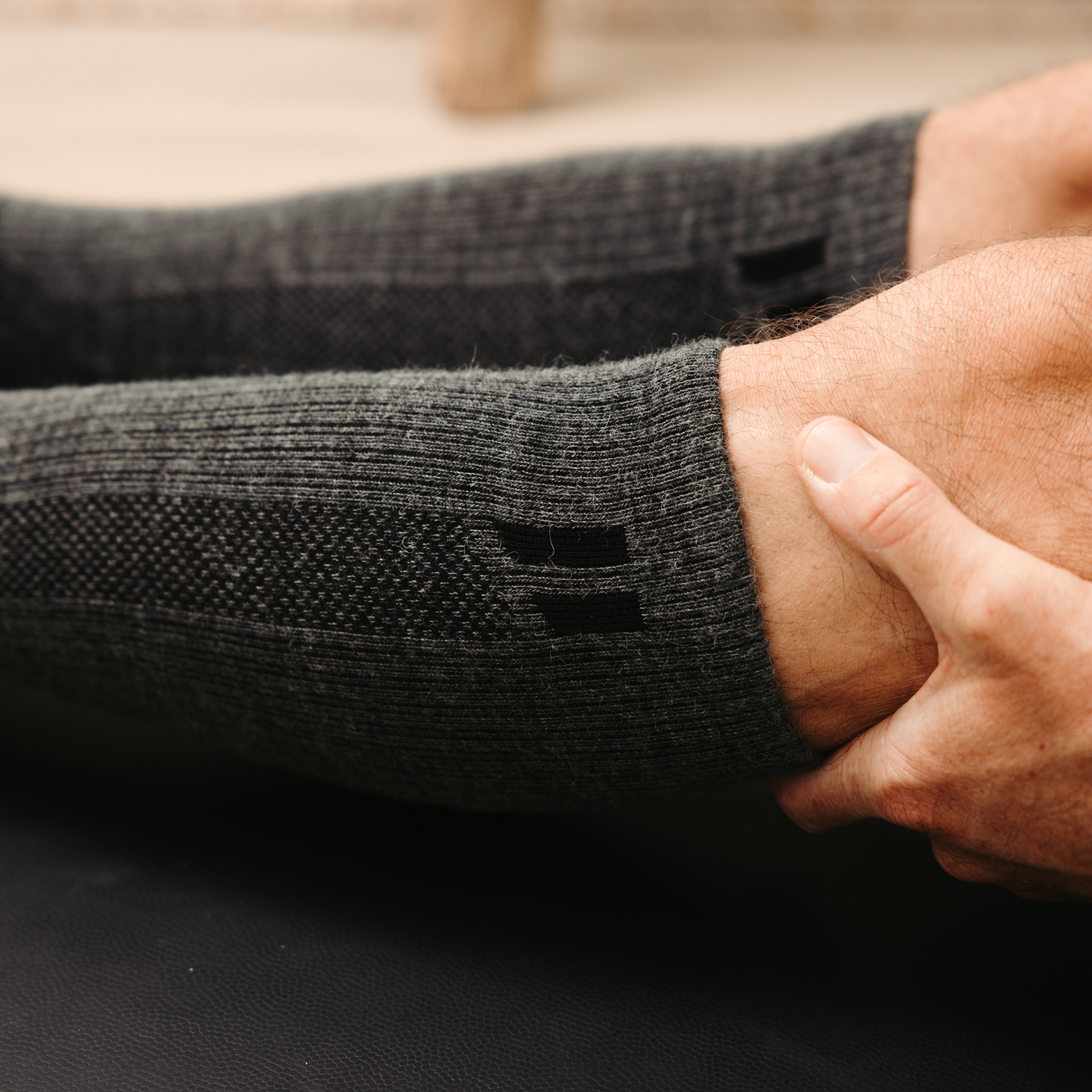 A close-up of a hand holding a person's lower leg wearing a gray compression sleeve.