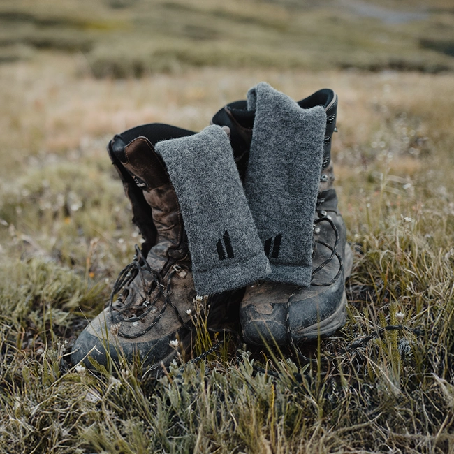 Worn hiking boots with gray socks in a grassy field.