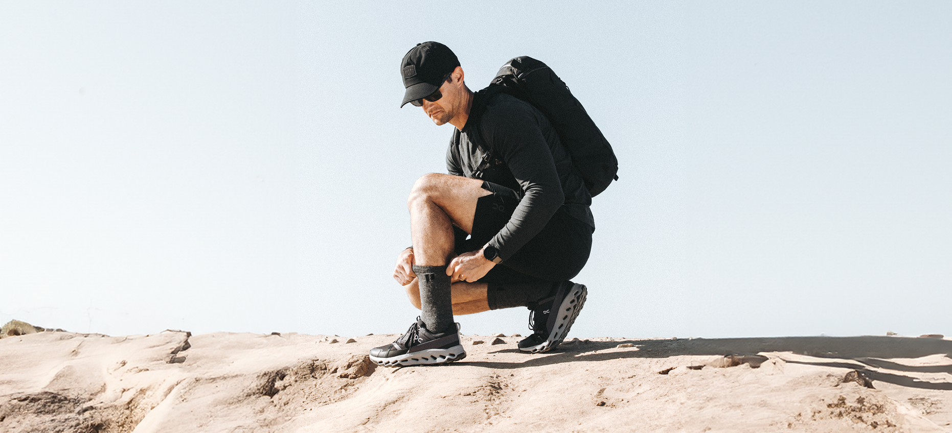 Person in athletic gear tying shoelaces on a rocky surface.