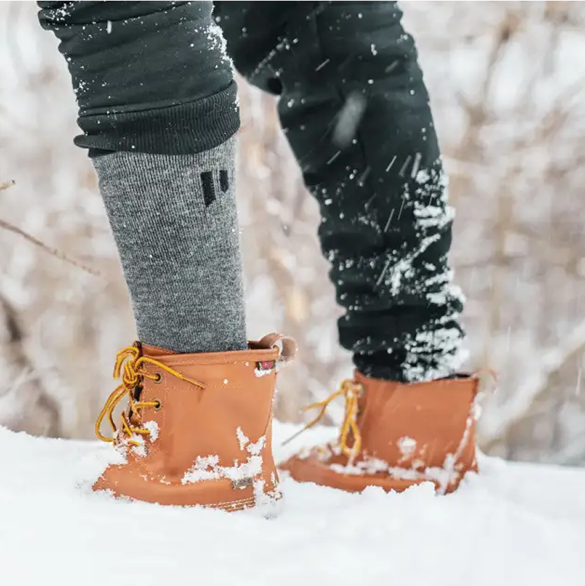 Person wearing boots and wool socks standing in snow.