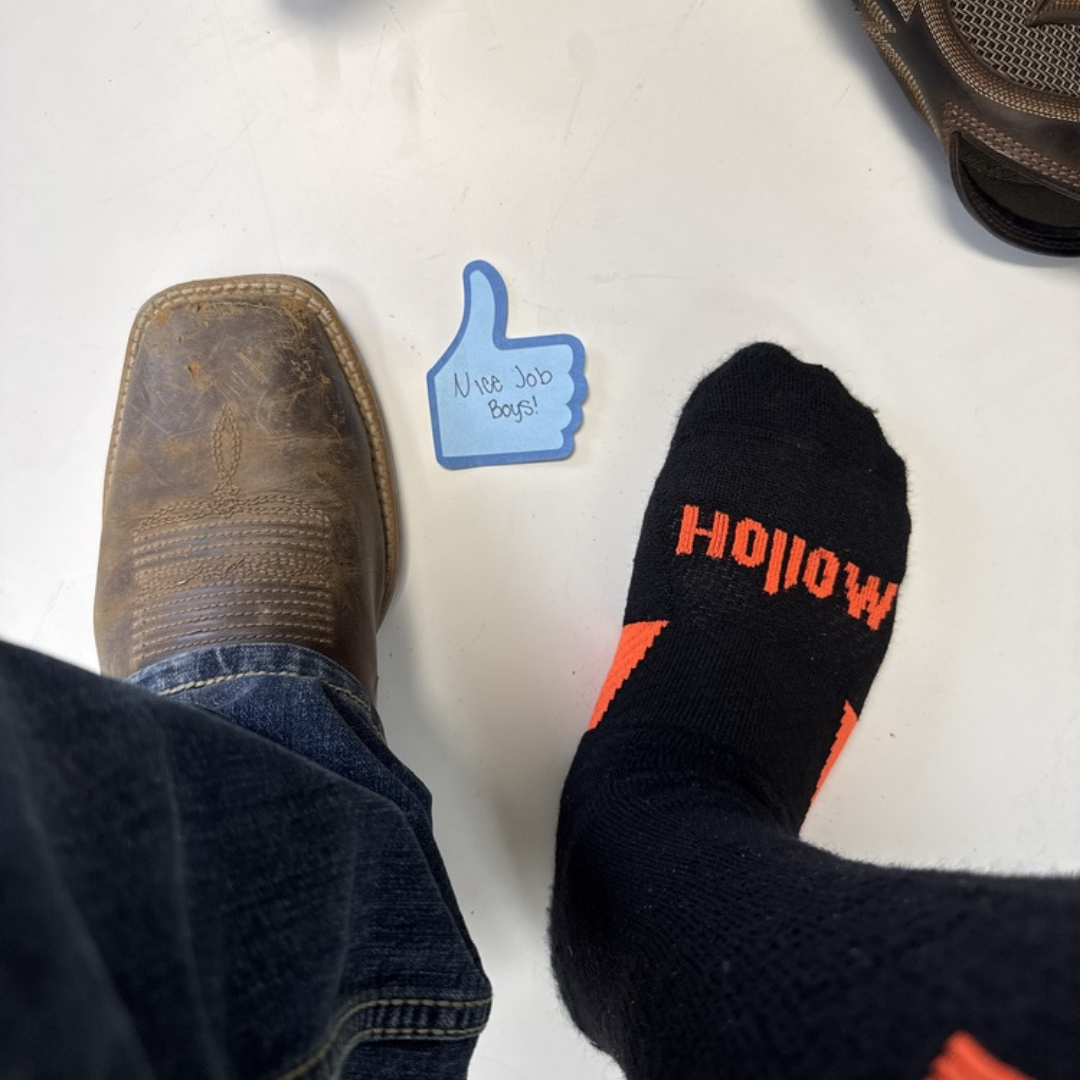 A top-down view of one foot in a boot and the other in a sock, with a thumbs-up note.