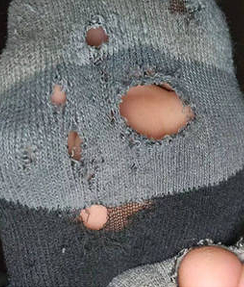 Close-up of a gray knitted fabric with multiple holes.