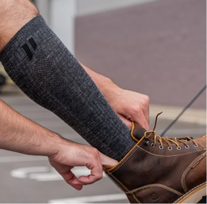 Person wearing a gray compression sleeve and brown boot.