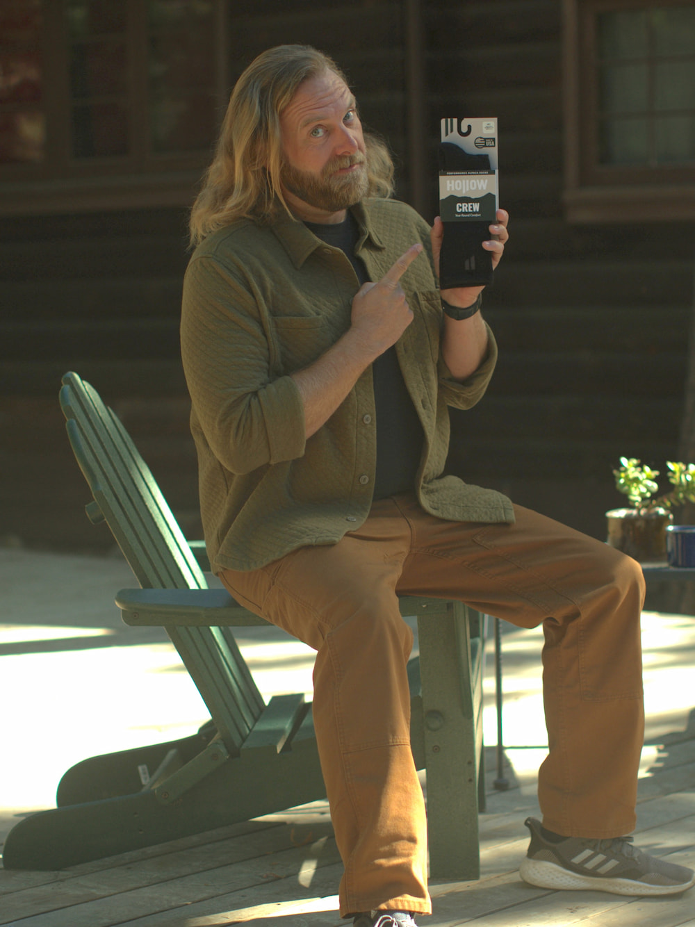 Man sitting on a chair, pointing at a product box outdoors.