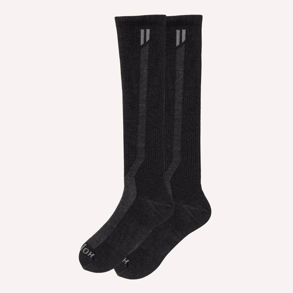 A pair of long black socks with textured details, set against a plain off-white background.
