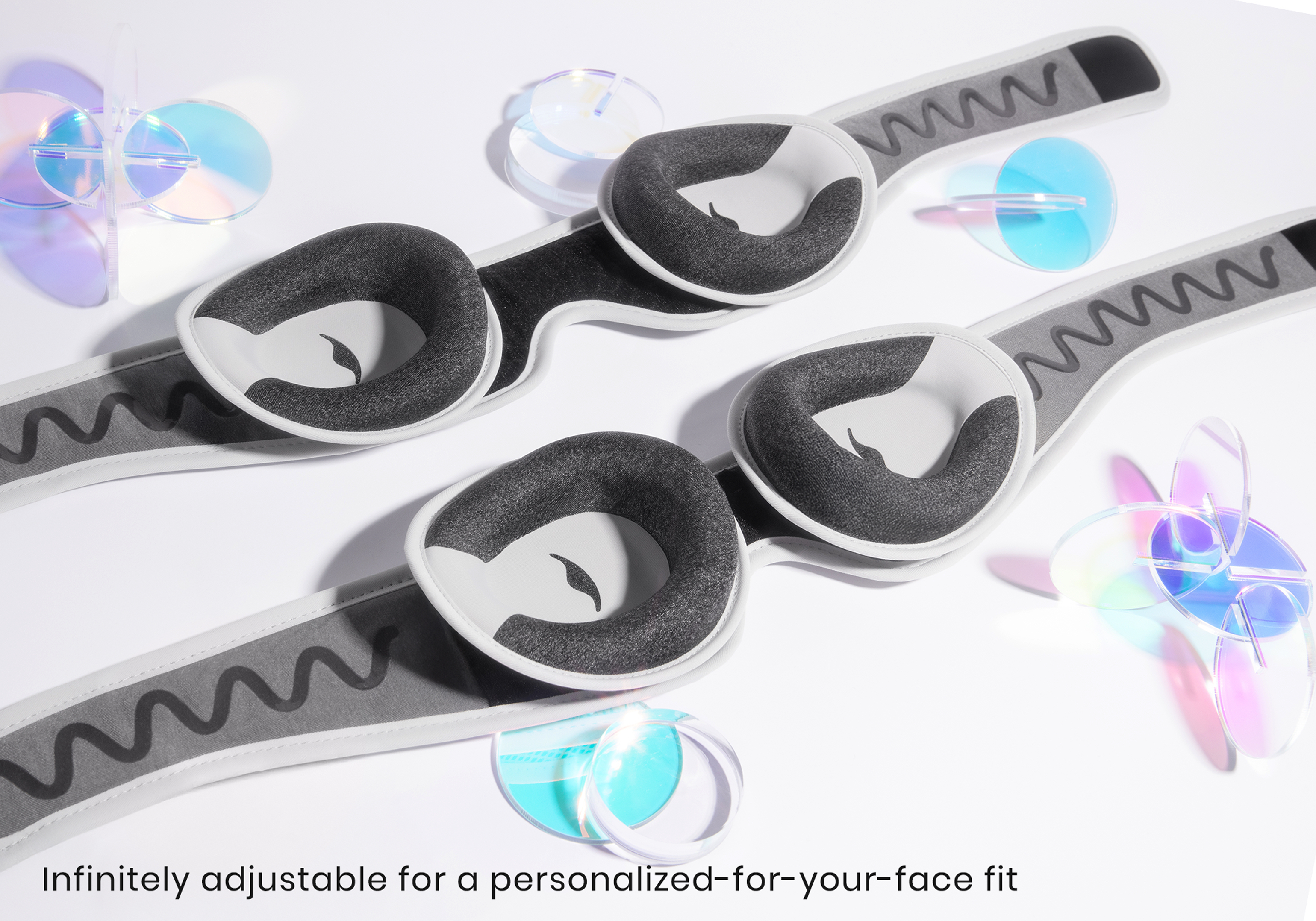 Two pairs of grey and white padded eye masks with wavy-patterned straps on a white surface.