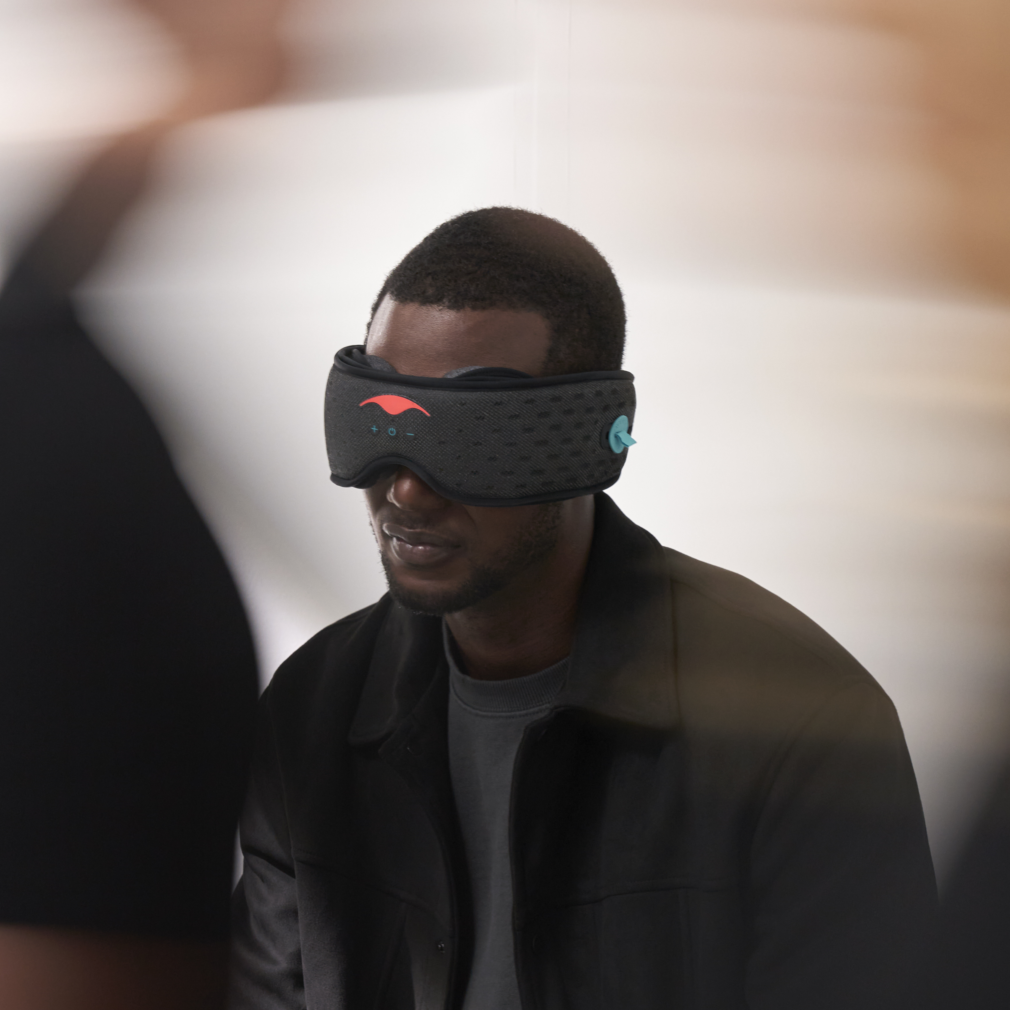 Person wearing a black eye mask with red and blue accents.