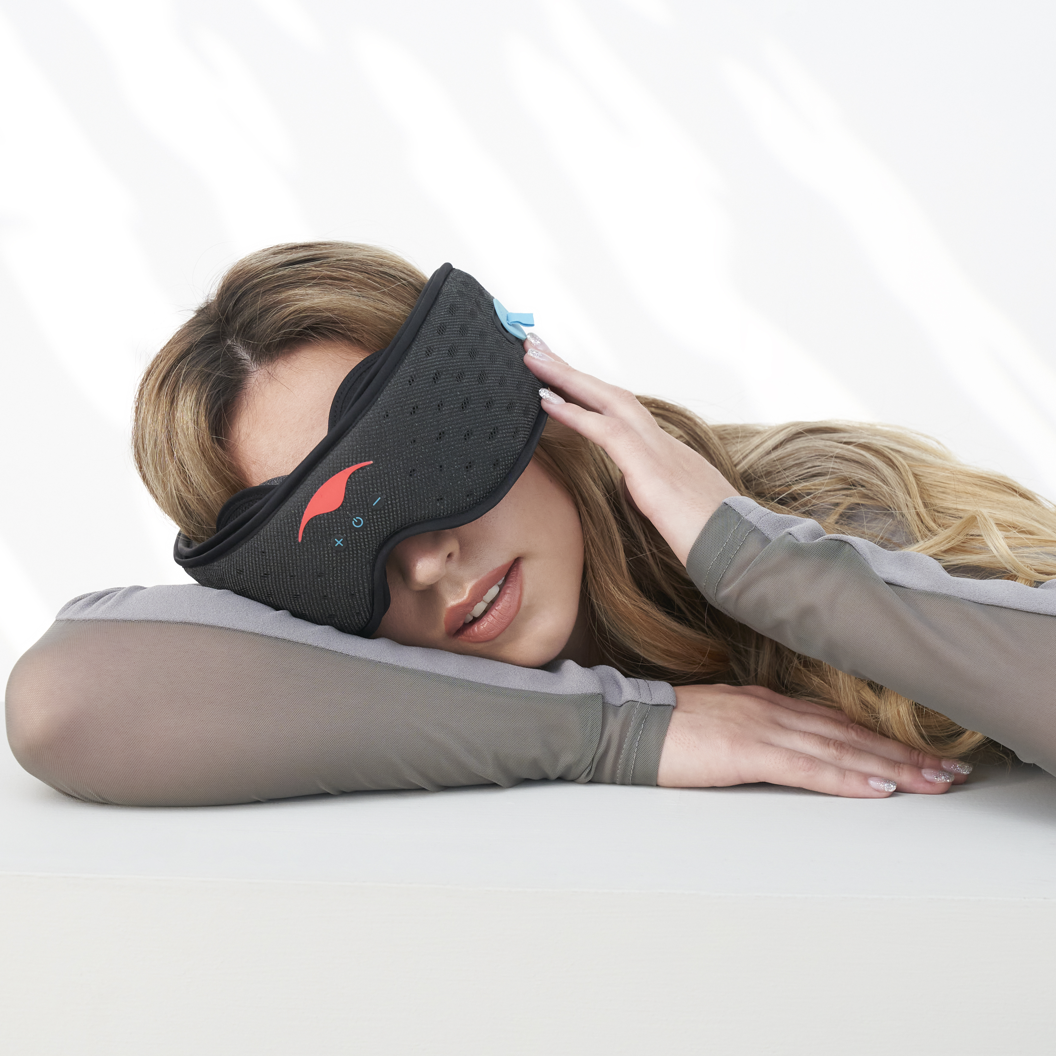 Person wearing a black sleep mask, resting on a white surface.