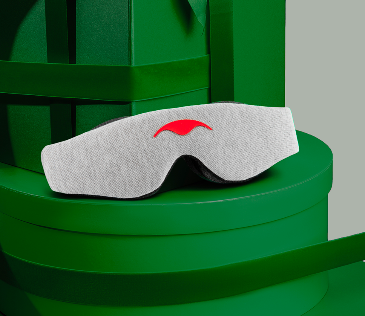 Gray eye mask with red design on green background.