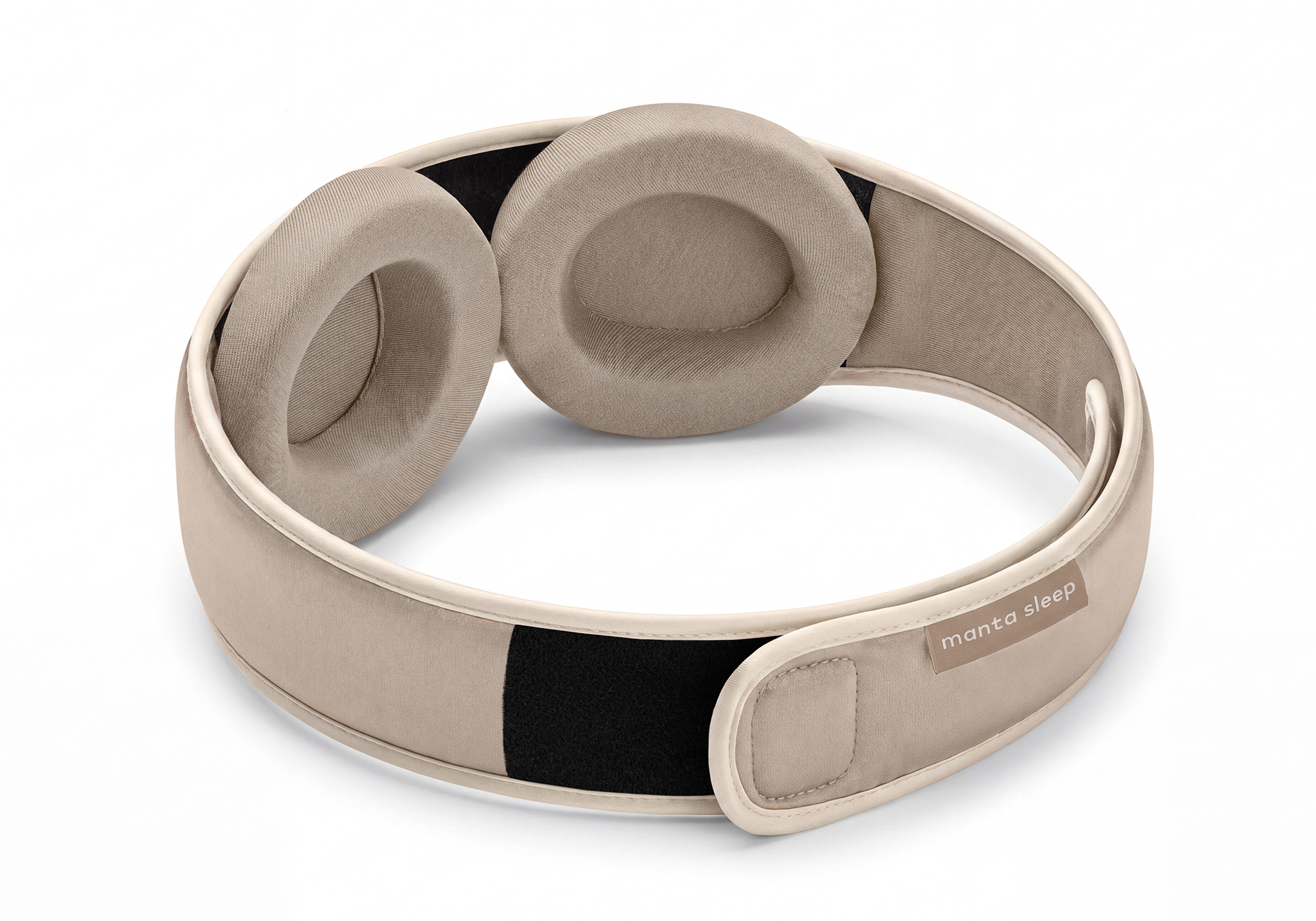 A beige Manta Sleep mask with two padded, circular eye cups, resting on a white surface.