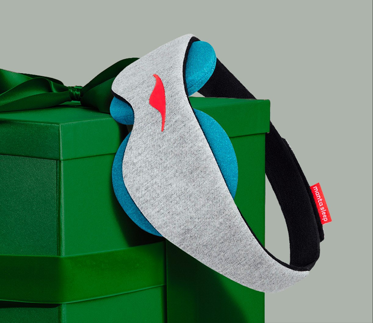 Gray and blue sleep mask on a green gift box with a ribbon.