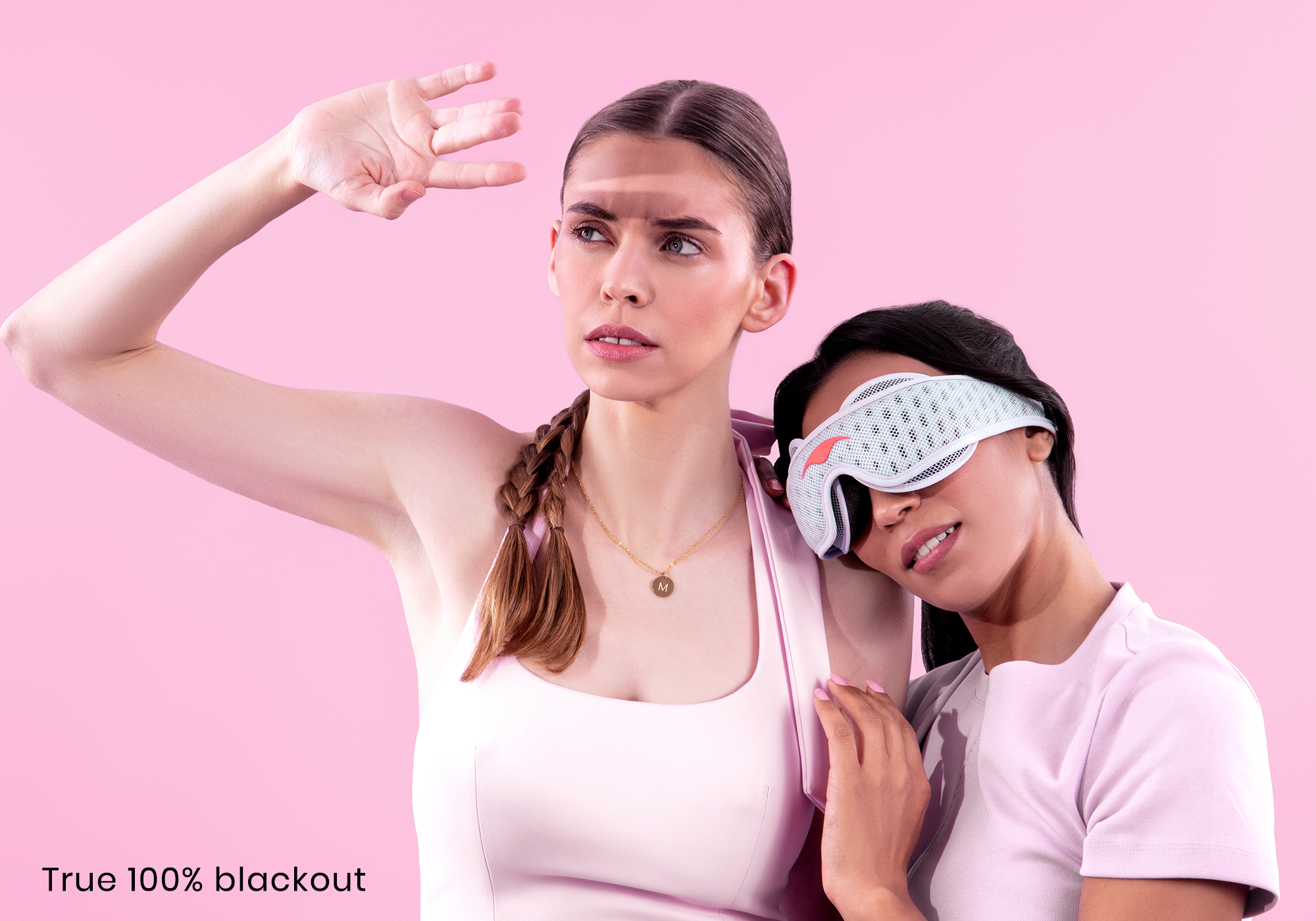 Two women in pink clothing; one wears a sleep mask, the other shields her eyes.