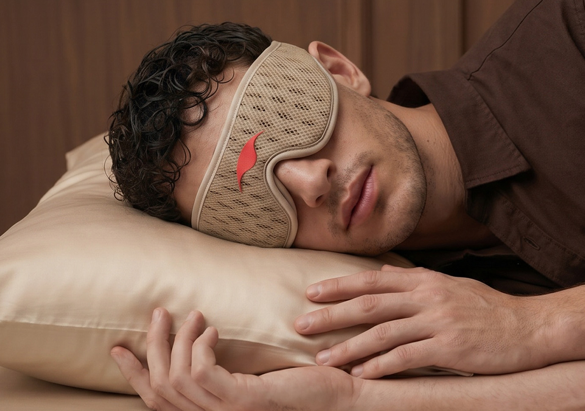 A man wearing a beige mesh sleep mask rests his head on a pillow.