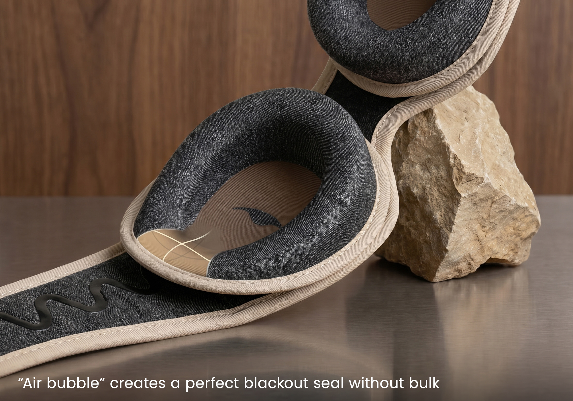 Angled view of a sleep mask inclined against a rock, showing the padded eye cups and anti-slip strap.