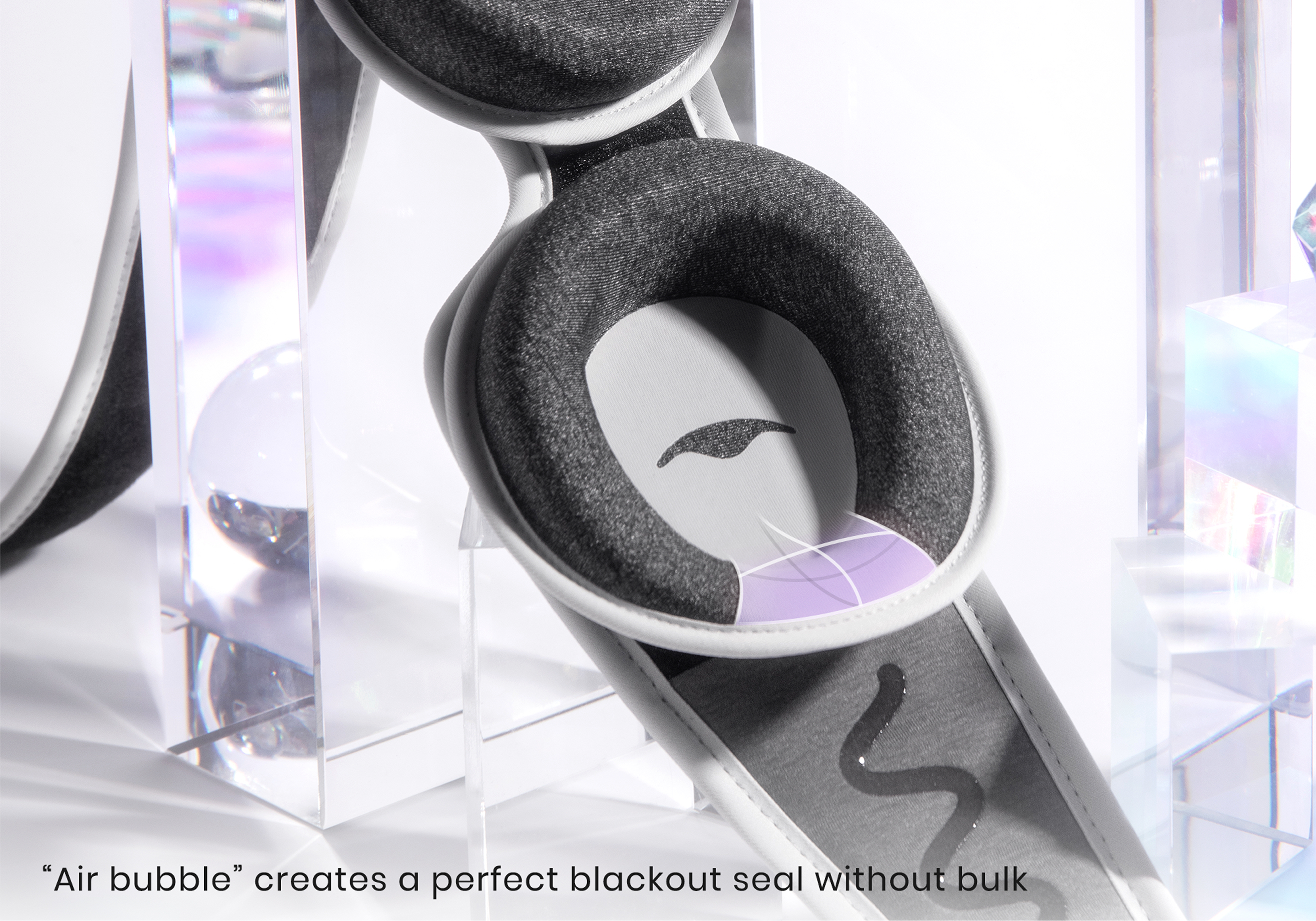 A close-up product shot of a grey and white sleep mask showing the padded eye cups and air bubble technology.