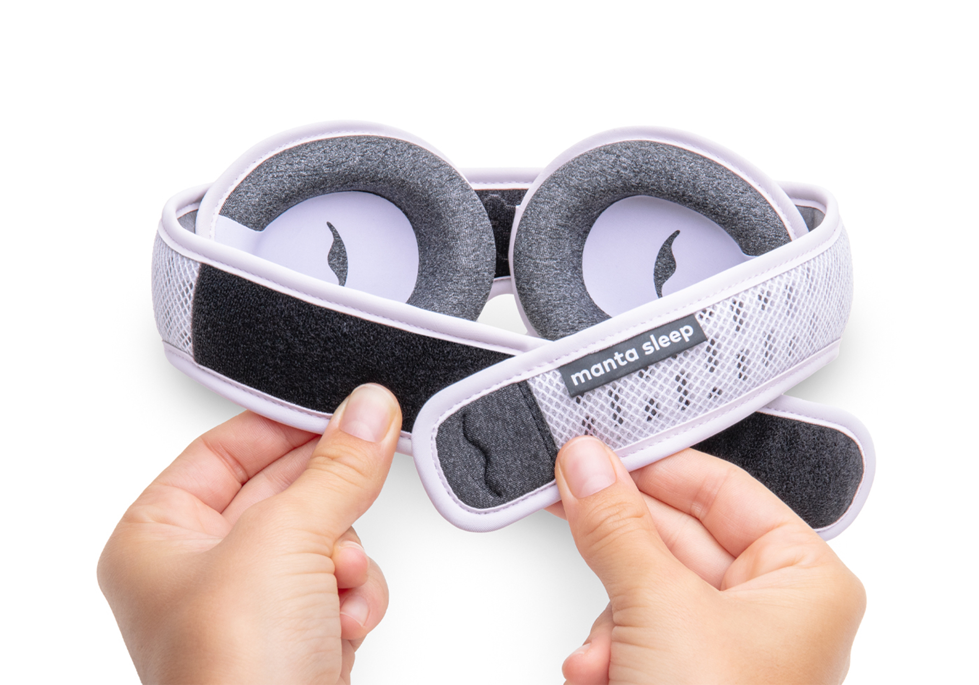 Hands holding a manta sleep mask with adjustable straps.