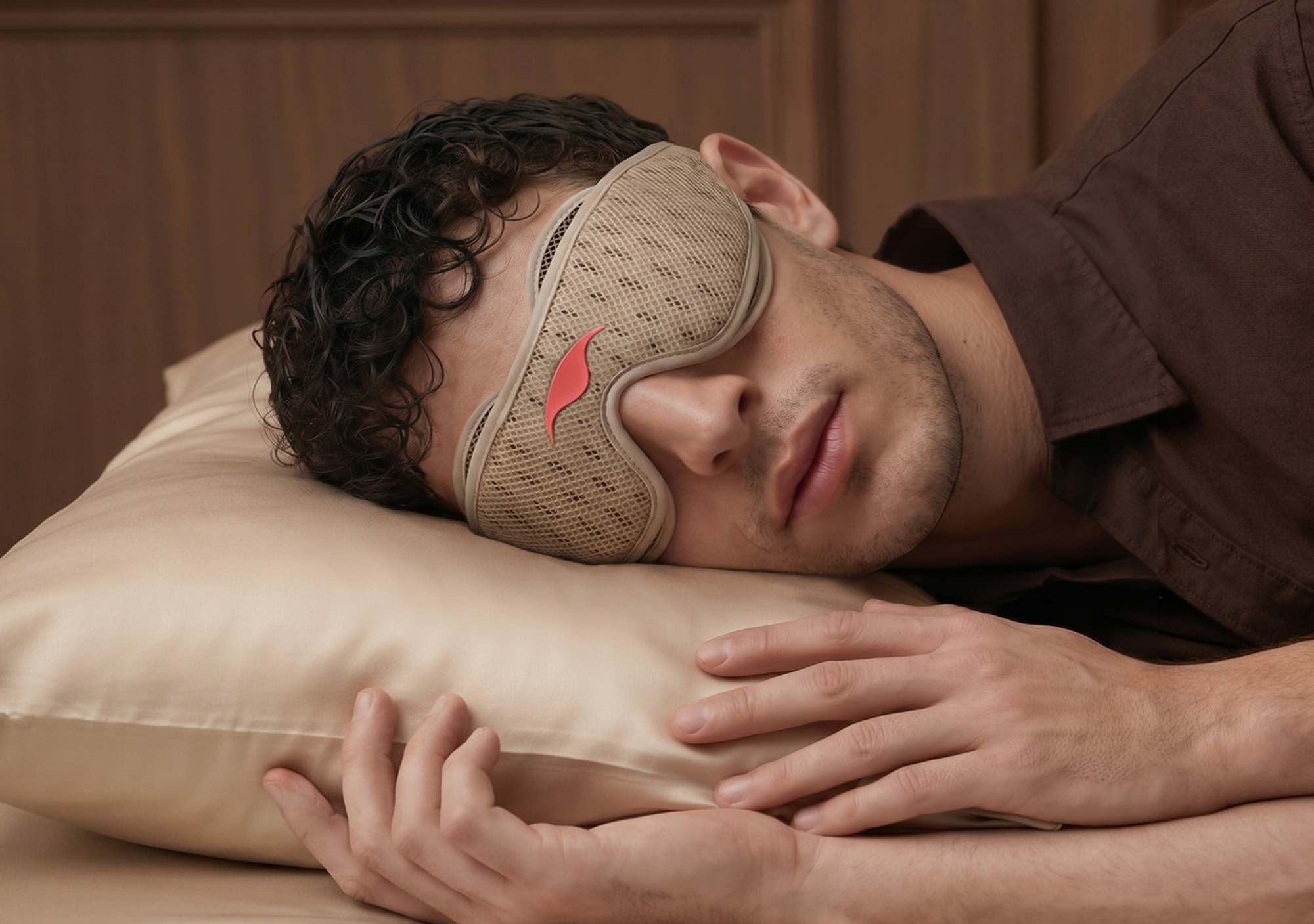 A man wearing a mesh sleep mask rests his head on a satin pillow.