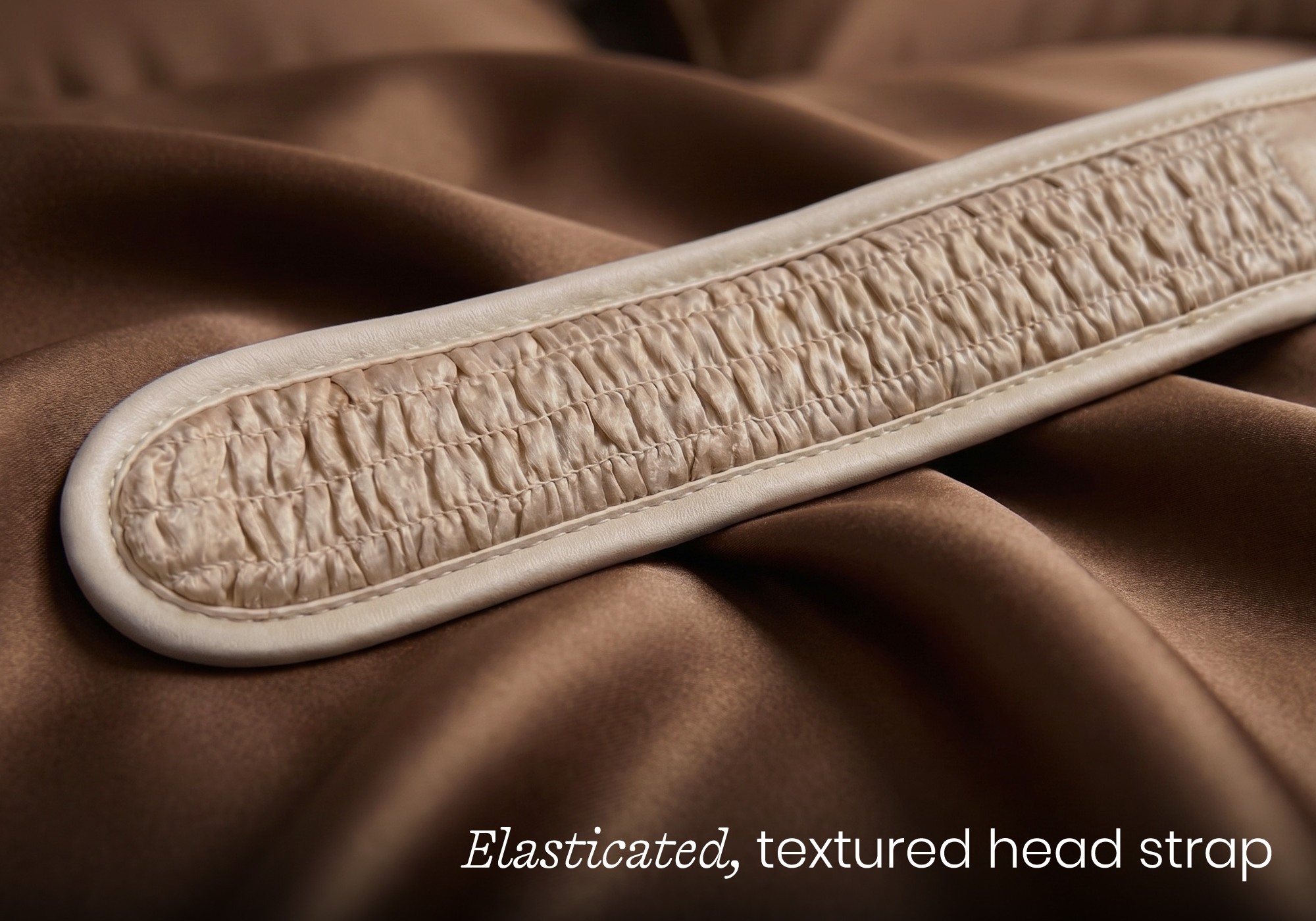 A close-up of a light-colored, elasticated, textured strap resting on a draped piece of brown satin fabric.