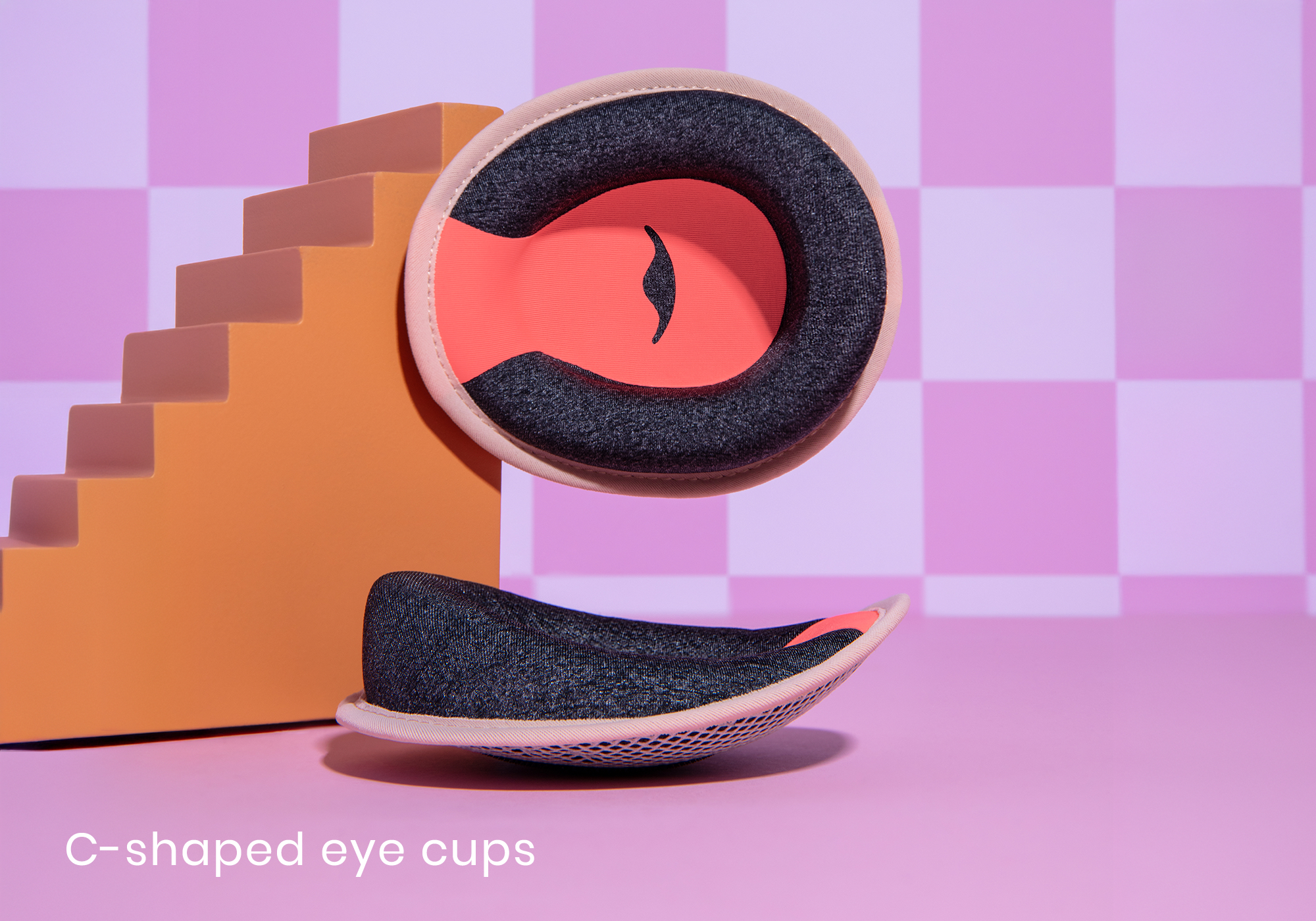 C-shaped eye cups on a pink and orange checkered background.