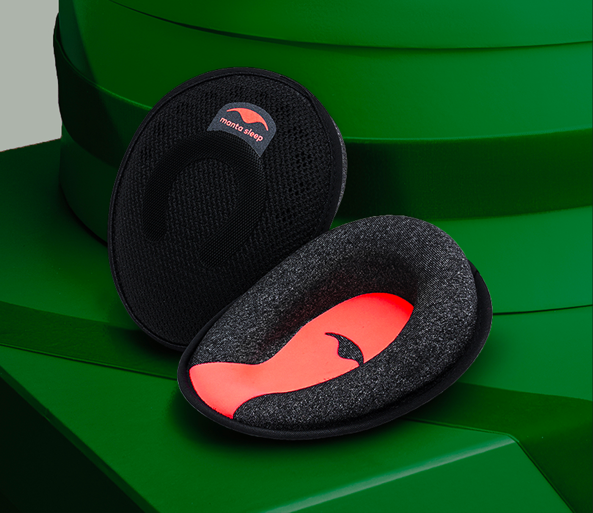 Two black foam pads with red inserts on a green background.