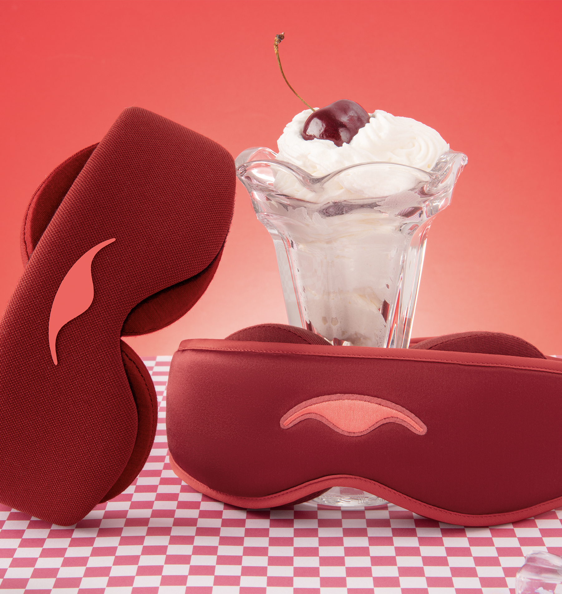 Ice cream sundae with cherry, surrounded by two red sleep masks.