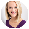 Smiling person with short blonde hair in a purple top, against a white background.