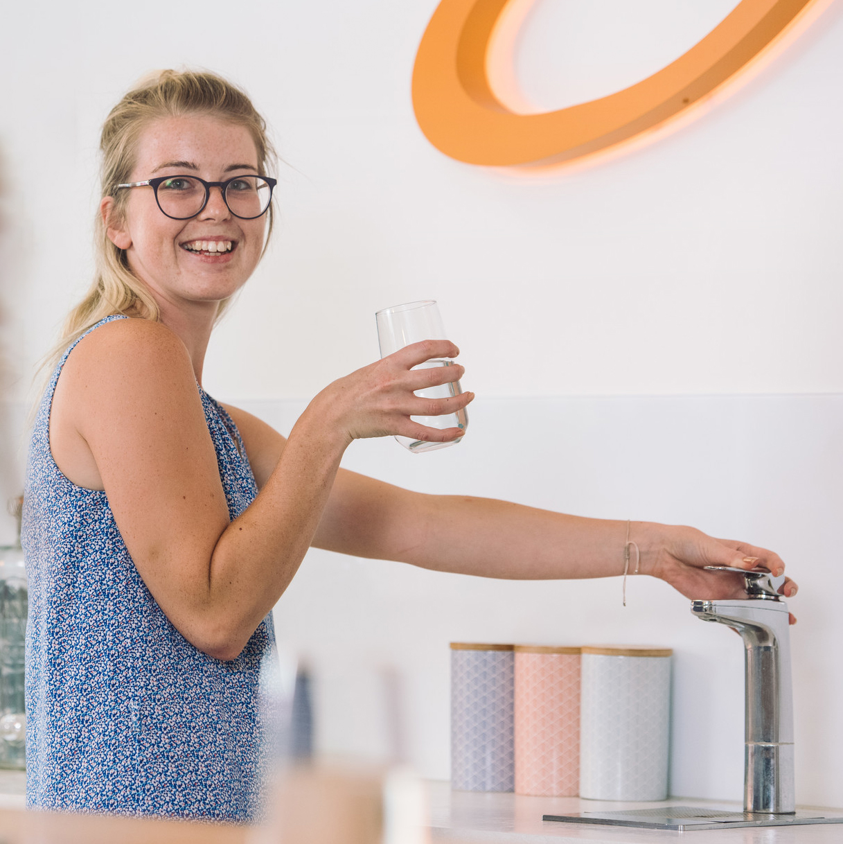 Person filling a glass with water at a kitchen sink.