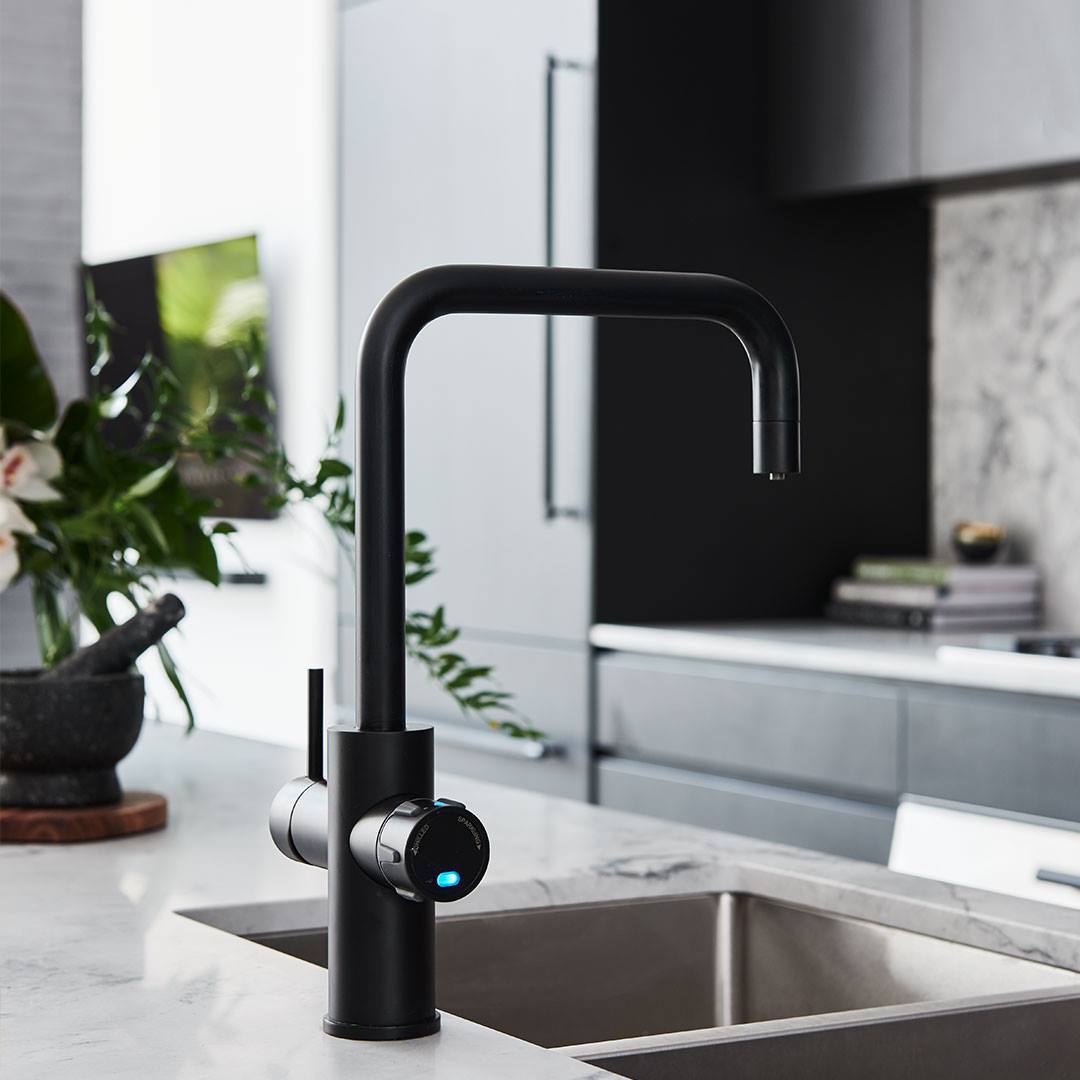 Modern black kitchen faucet with a sleek design on a marble countertop.