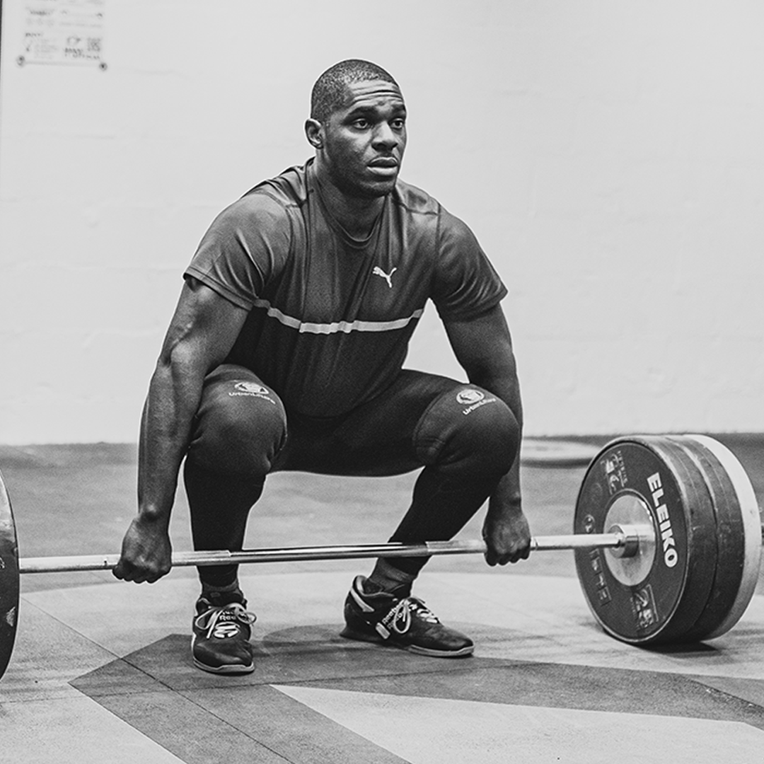 Man deadlifting a barbell in a gym.