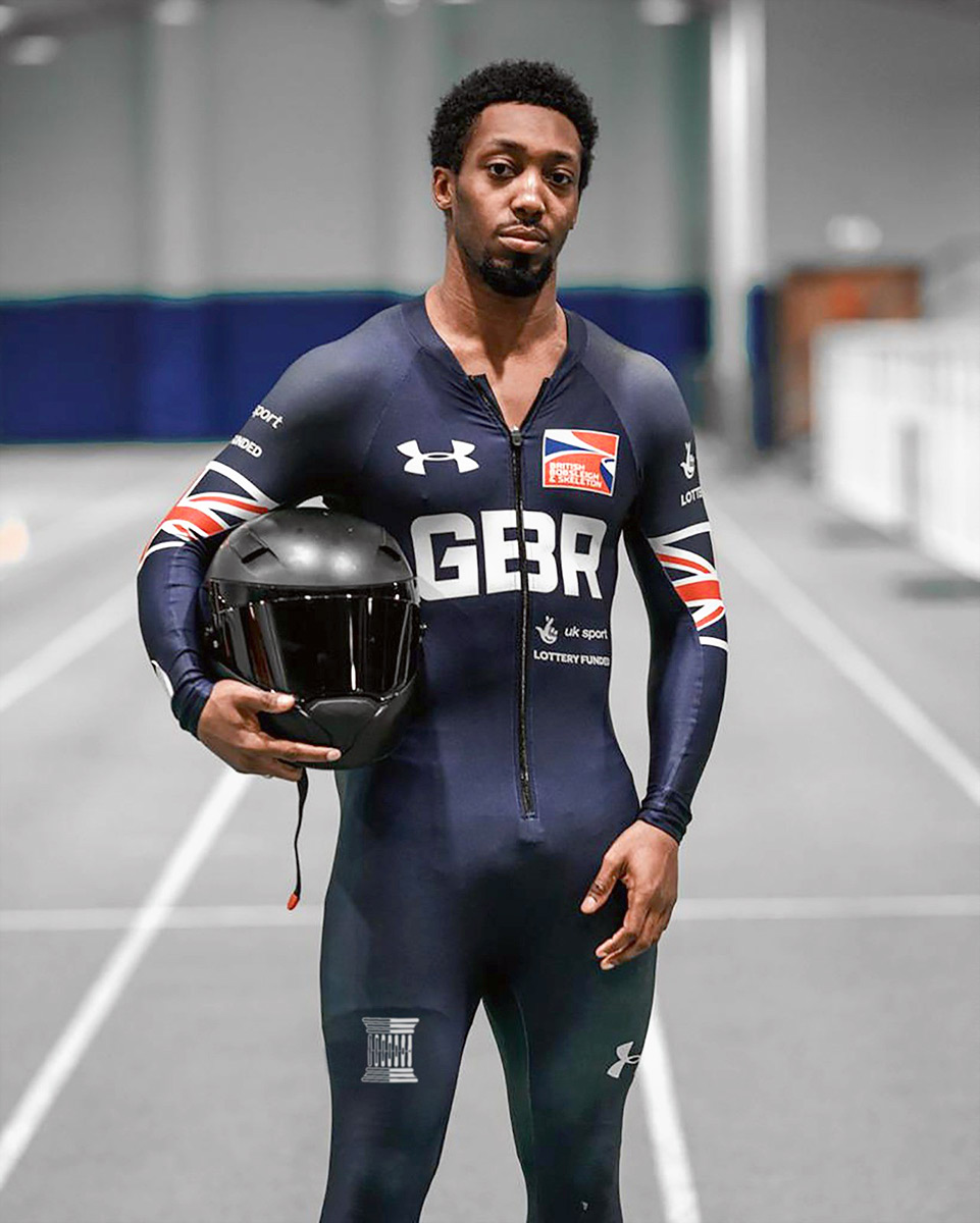 Athlete holding a helmet, wearing a GBR sports suit in an indoor track setting.