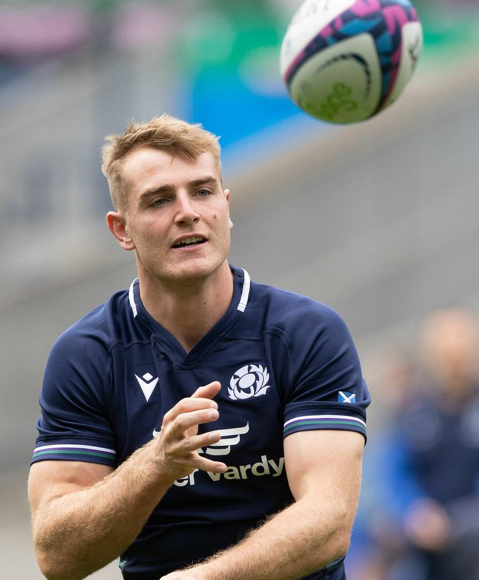 A rugby player in a blue jersey catching a ball.