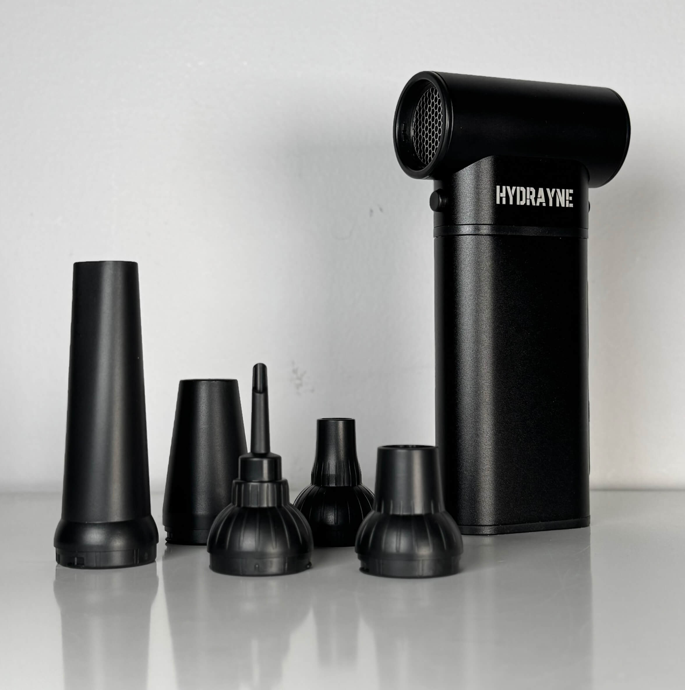 Black device with multiple nozzle attachments on a white surface.
