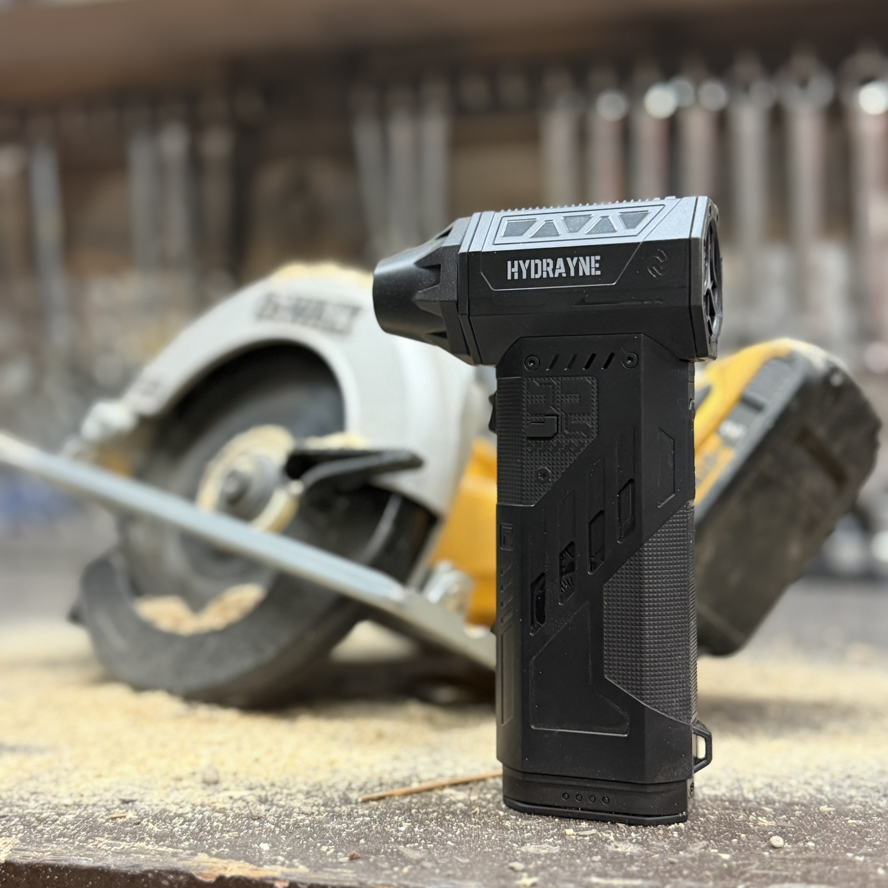 Black handheld device with multiple nozzle attachments on a grey surface.